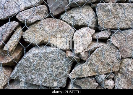 Gabion wall closeup. Textured background. Gabion is stones in wire mesh used for erosion control and slope reinforcement Stock Photo