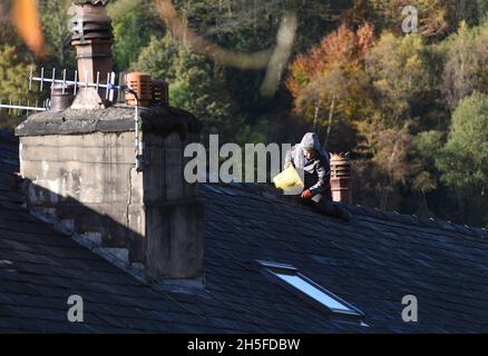 Builder man repairing roof on house without health and safety equipment Britain, Uk Stock Photo