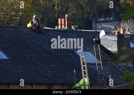 Builder man repairing roof on house without healty and safety equipment Britain, Uk Stock Photo