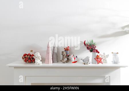 Decoration of the interior of the apartment for Christmas. A garland of carved wood figures. Candles and ceramic figurines on a fake fireplace. Copy s Stock Photo