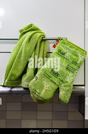 POZNAN, POLAND - Oct 12, 2018: A close up of Green oven glove and green towel hanging on a cupboard handle in Poznan, Poland Stock Photo