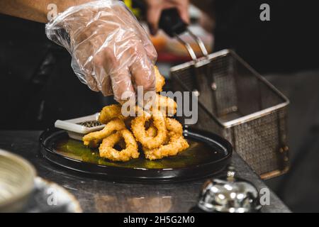 chef prepares deep-fried onion rings in the restaurant kitchen. Stock Photo