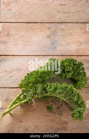 Curly leaves of kale or green leaf cabbage on rustic wooden planks, vertical format with large copy space for an announcement poster, copy space, top Stock Photo