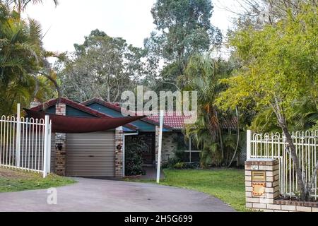 Cute brick Australian house with tile roof and awning snuggled back into the tropical rainforest Stock Photo
