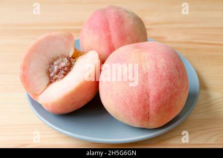 Fresh Ripe Peach Whole Fruits and a Cut Fruit on Blue Plate Served on Wooden Table Stock Photo