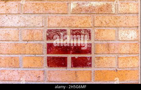 Stockholm, Sweden - April 15, 2021: Centered pattern of red glazed bricks on orange brick-wall Stock Photo