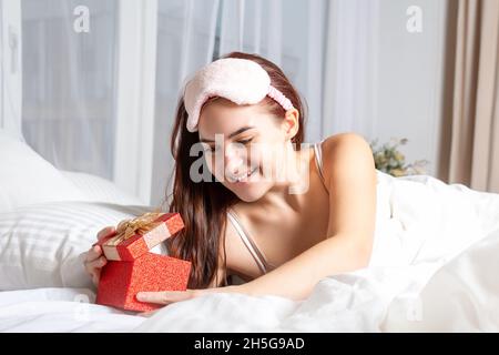 Young woman wakes up and finds gift. Stock Photo
