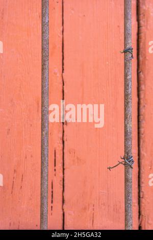 Stockholm, Sweden - April 15, 2021: Two rusted iron sticks, one with twisted wire, on red wooden background Stock Photo