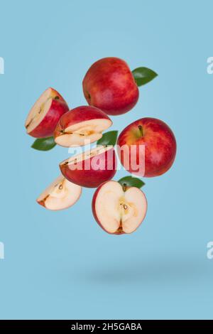 Minimal fruit concept with fresh sliced and whole apple floating in the air isolated on blue background. Vitamins, healthy diet concept. Creative conc Stock Photo