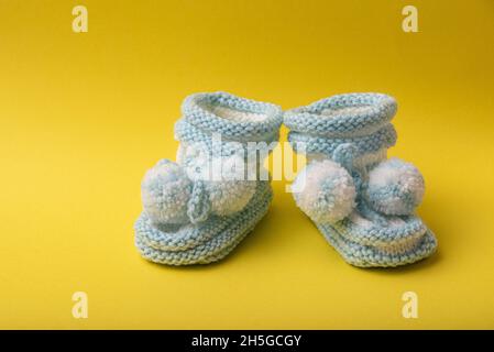 homemade knitted shoes for newborn boys on yellow background Stock Photo