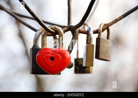 Heart shaped padlock in a park. Locks hanging on sky background, symbol of eternal love Stock Photo
