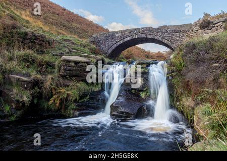 The River Dane flows under the packhorse bridge at Three Shires Head where the counties of Cheshire, Staffordshire and Derbyshire meet in the Peak Dis Stock Photo