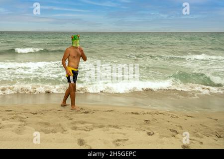 Caucasian male with a frog head on the beach Stock Photo