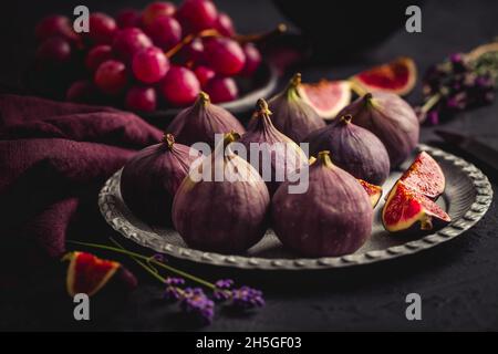 Organic fresh figs with red grapes and lavender on dark background Stock Photo