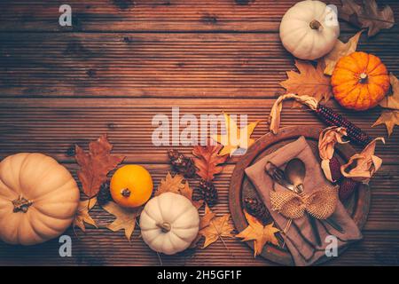 Autumn flat lay with plate setting, pumpkins and autumn leaves with copy space Stock Photo