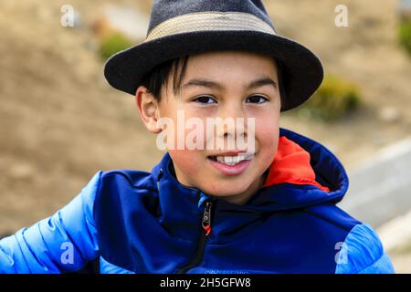 A Young Inuit boy wearing a hat in the Village of Tasiilaq looks at the camera. Stock Photo