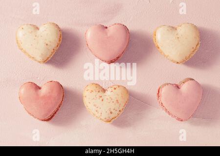 Delicious French macarons in heart shape on pink background Stock Photo