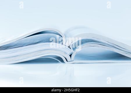 Stack of open magazines in blue tone on white background with copy space Stock Photo
