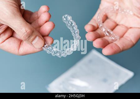 Hands holding transparent aligners. Invisalign orthodontics concept Stock Photo
