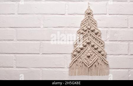 Christmas tree ornament macrame from white natural cotton threads on a white background. Festive christmas tree braided from yarn on a white backgroun Stock Photo