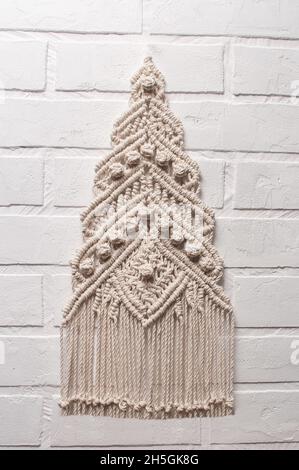 Christmas tree ornament macrame from white natural cotton threads on a white background. Festive christmas tree braided from yarn on a white backgroun Stock Photo