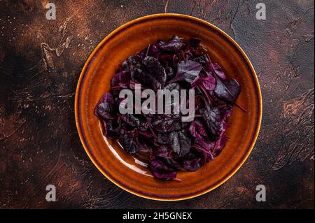 Raw Ruby or red chard salad Leafs on a rustic plate. Dark background. Top view Stock Photo
