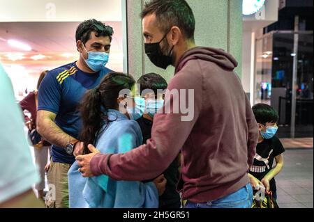 Sacramento, CA, USA. 4th Nov, 2021. Principal Nate McGill, center, Ethel I. Baker Elementary School, gathers Rahmatullah, left, and his three school children, Pakiza, 9, Faizan, 8, and Raihan, 6, upon their arrival to Sacramento International Airport on Thursday, Nov. 4, 2021. They along with their mother Huma had been trapped in Afghanistan after the fall to the Taliban. Earlier in the day McGill along with other school faculty went shopping for food and supplies to welcome them home before heading to the airport. (Credit Image: © Renée C. Byer/ZUMA Press Wire) Stock Photo