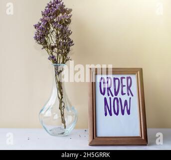 Writing displaying text Order Now. Business concept confirmed request by one party to another to buy sell Empty Picture Frame With Flower Vase Stock Photo