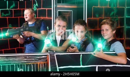 Boy and girls aiming laser guns at other players during laser ta Stock Photo