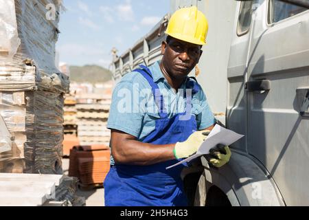 Portrait of an african american worker standing in a warehouse near a car Stock Photo