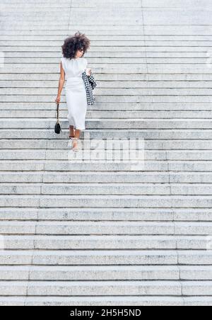 Woman alone walking down the stairs looking to the side Stock Photo