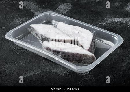 Frozen halibut pack set, on black dark stone table background, top view ...