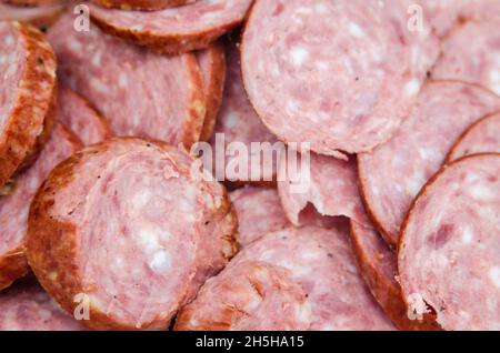A background of chopped pieces of sausage. High -quality smoked red sausage salami with a lot of fat and spices background Stock Photo