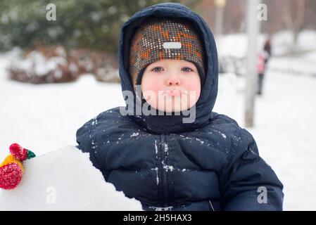 a little child looks out of the snow or pieces of ice. A child plays with snow Stock Photo