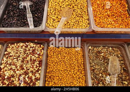 A lot of the sorted dried fruits and nuts, pistachios, peanut, prunes in square ware. Various dried fruits and nuts in market Stock Photo