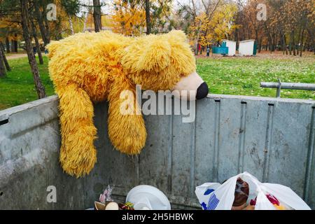 Abandoned teddy bear in the trash can. The symbol of leaving childhood, growing up Stock Photo