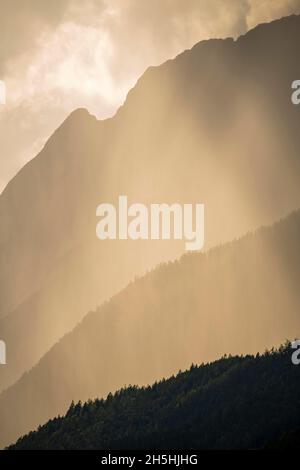 Rain clouds on a mountain flank, from behind the sun shines into the clouds, Karwendel Mountains, Tyrol, Austria Stock Photo