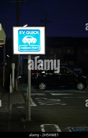 EV Quick charging point for electric vehicles. Blue light up sign. Stock Photo