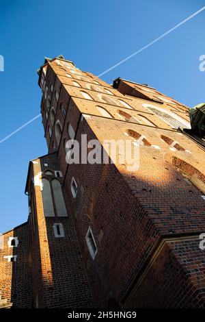 Tower of St. Mary's Basilica at Main Market Square, Krakow Stunning view photo from below of tall red-brick tower against clear blue sky on sunny day Stock Photo