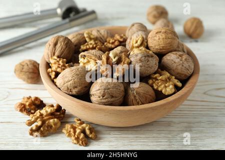 Nutcracker and bowl of walnuts on white wooden background Stock Photo