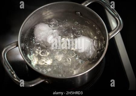 Two white eggs are boiled in a saucepan. Stock Photo