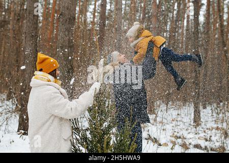 Dad lifting his happy little son up in the air during family stroll in forest Stock Photo