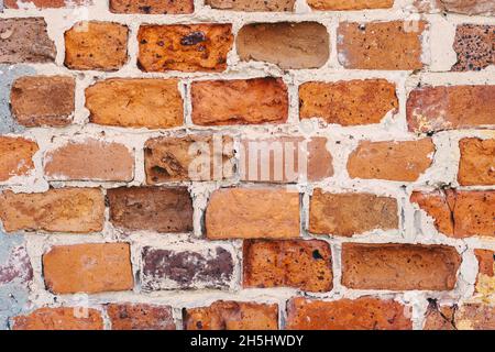 old red brick wall covered with green moss in places background Stock Photo