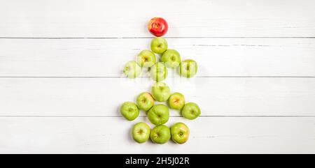 Edible Christmas tree made of green apples with red apple as star on white wooden backdrop. Xmas food banner. Holiday, food art. Banner for festive pa Stock Photo
