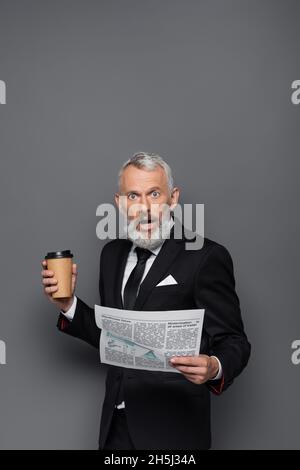 shocked bearded man holding newspaper with fake news in front of eyes ...