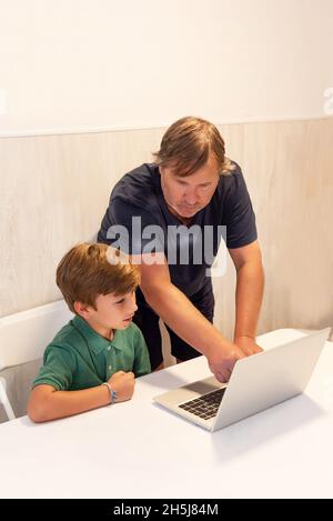 Father explaining to his son how to do his homework on a laptop computer Stock Photo
