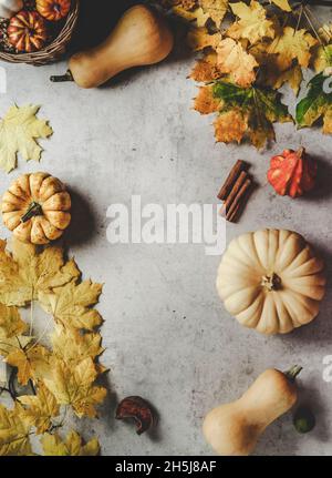 Autumn background frame with various pumpkins and yellow autumn leaves, cinnamon and candles on grey table. Seasonal fall still life with copy space. Stock Photo