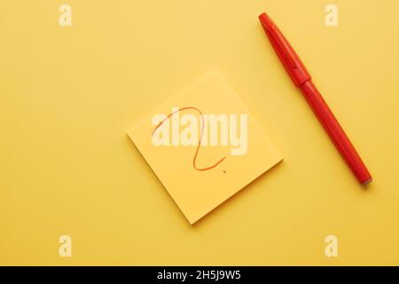 high angle view of question mark on paper on yellow background  Stock Photo