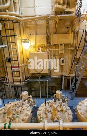 Yellow engine mounted on ship. Engine room on a old cargo boat ship. Large engines in the engine room. Stock Photo