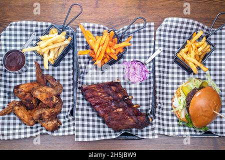 Sheffield UK –  01 May 2018: Rack of ribs, fried chicken and a pulled pork burger with fries – American diner barbecue food from Fire Pit, West Street Stock Photo